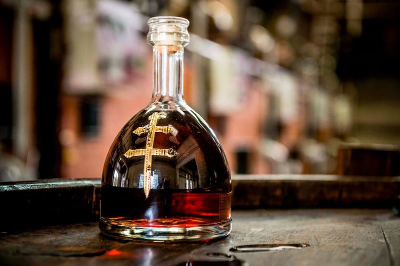 A close-up of a bottle of D’USSÉ Cognac on a wooden table.