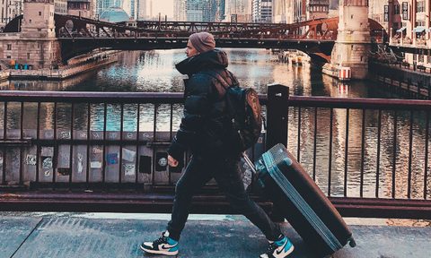 Man walking with a rolling luggage in the city.