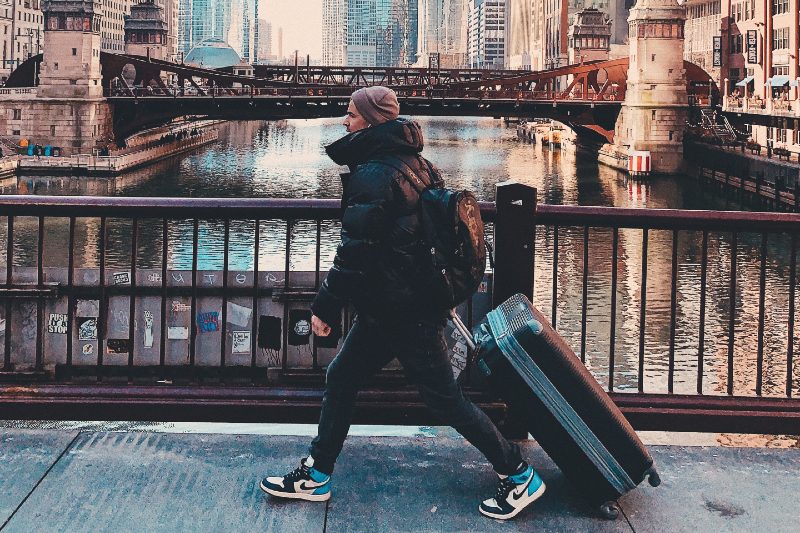 Man walking with a rolling luggage in the city.