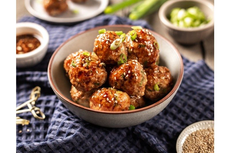 A bowl of chicken meatballs covered in oyster sauce.