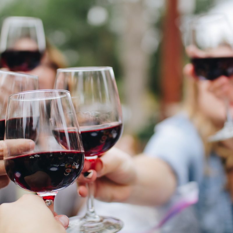 People cheering with glasses of red wine.