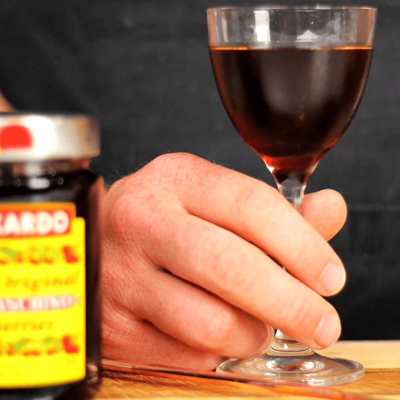 A close-up of Steve the Bartender's hand holding a glass of Reverse Manhattan.