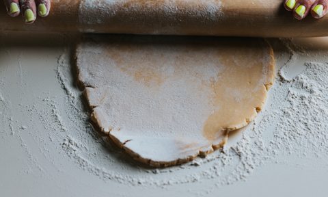Pie crust being rolled out on a table.