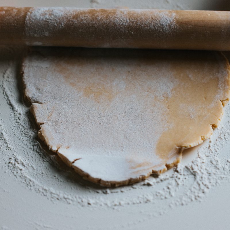 Pie crust being rolled out on a table.