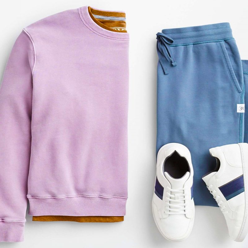 A pink long-sleeved shirt, blue jogging pants, and white sneakers on gray background.