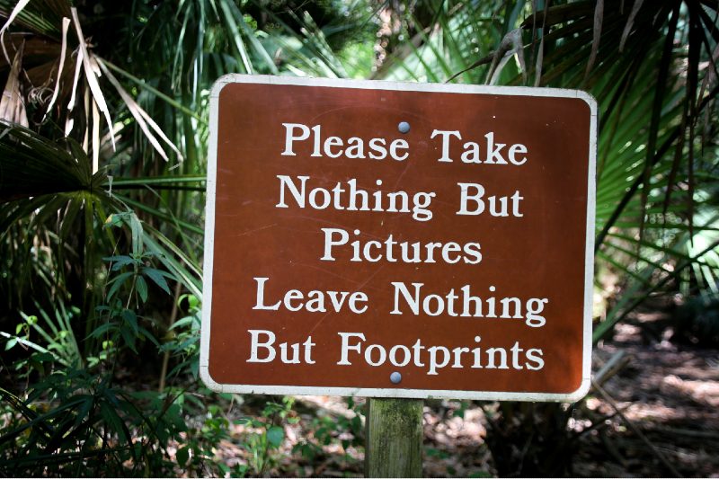 Sign that says "Please Take Nothing But Pictures Leave Nothing But Footprints"