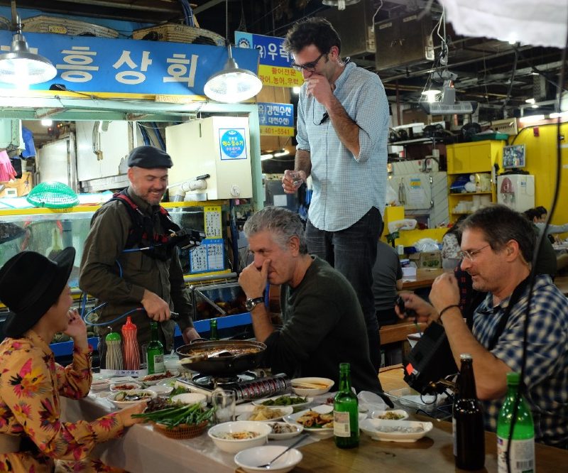 Anthony Bourdain, Tom Vitale and others sitting at a table.