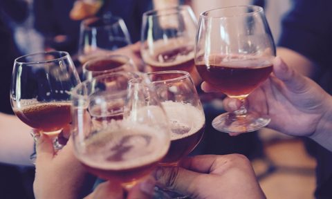 Hands holding tulip beer glasses offering a cheers.