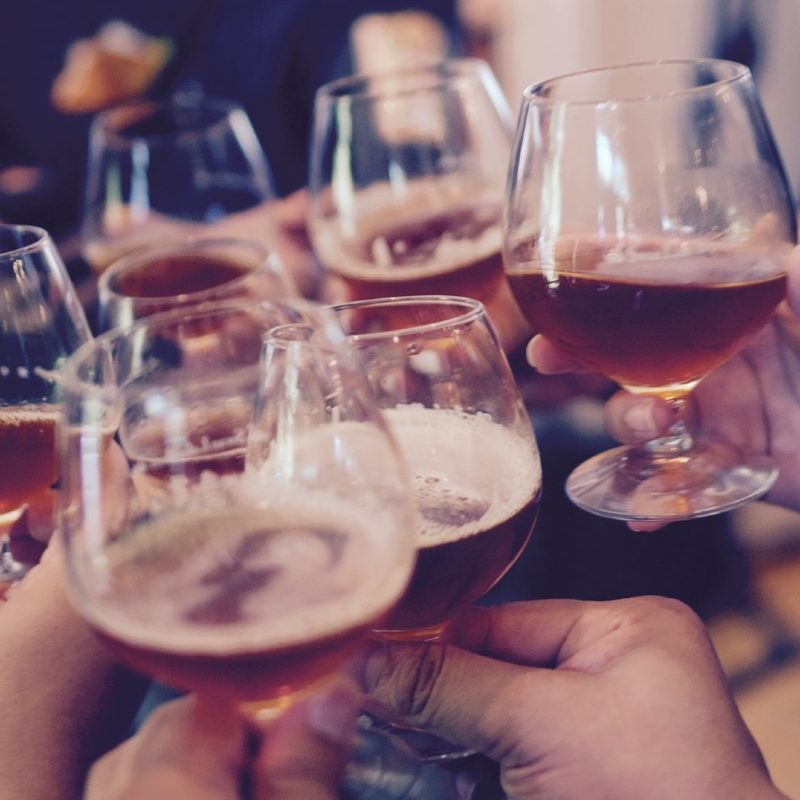 Hands holding tulip beer glasses offering a cheers.