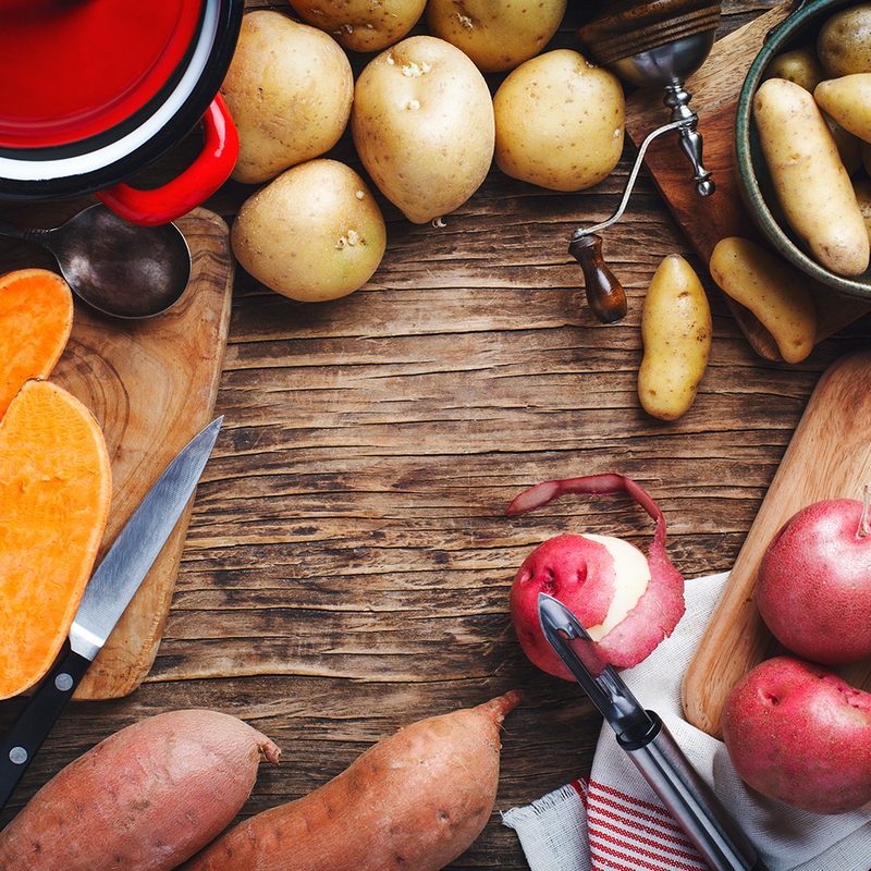 Variety of raw uncooked organic potatoes: red, white, sweet and fingers potatoes over wooden background.