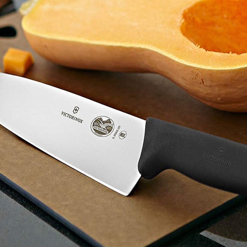 A Victorinox knife beside a butternut squash on a cutting board.