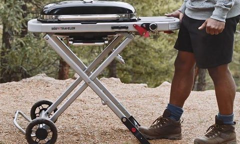 Weber traveler portable gas grill in a campground with man getting ready to grill.