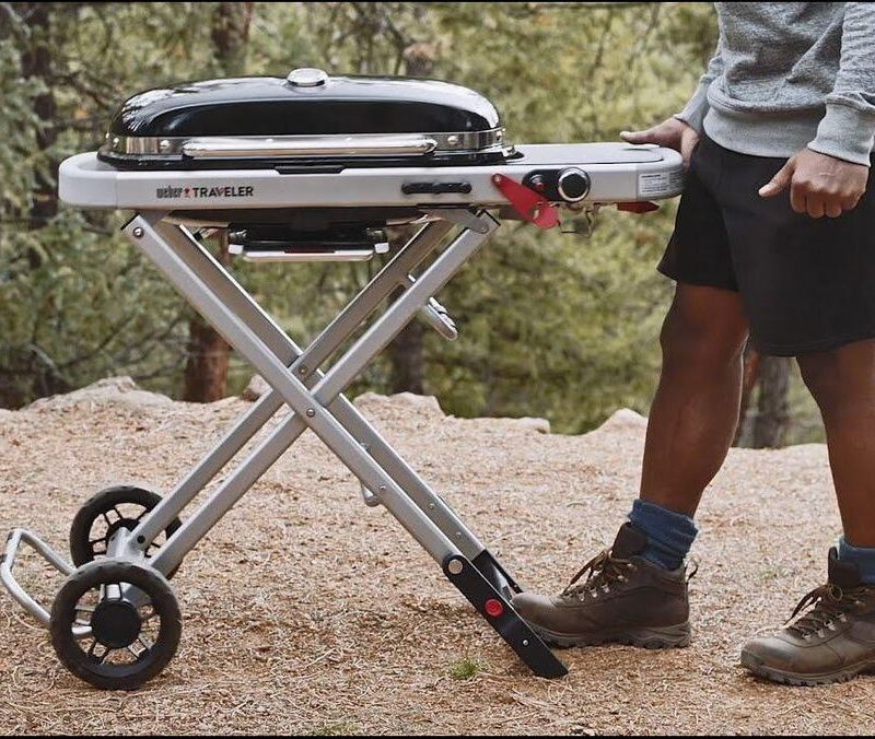 Weber traveler portable gas grill in a campground with man getting ready to grill.