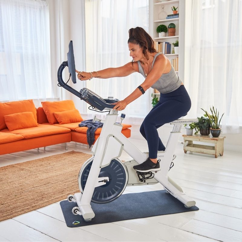 Woman working out on MYX II bike with tablet.