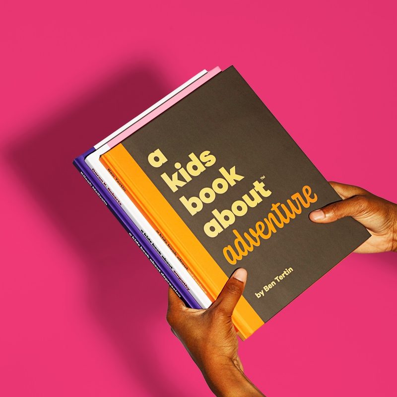 A Kids Book About Adventure with child holding book.