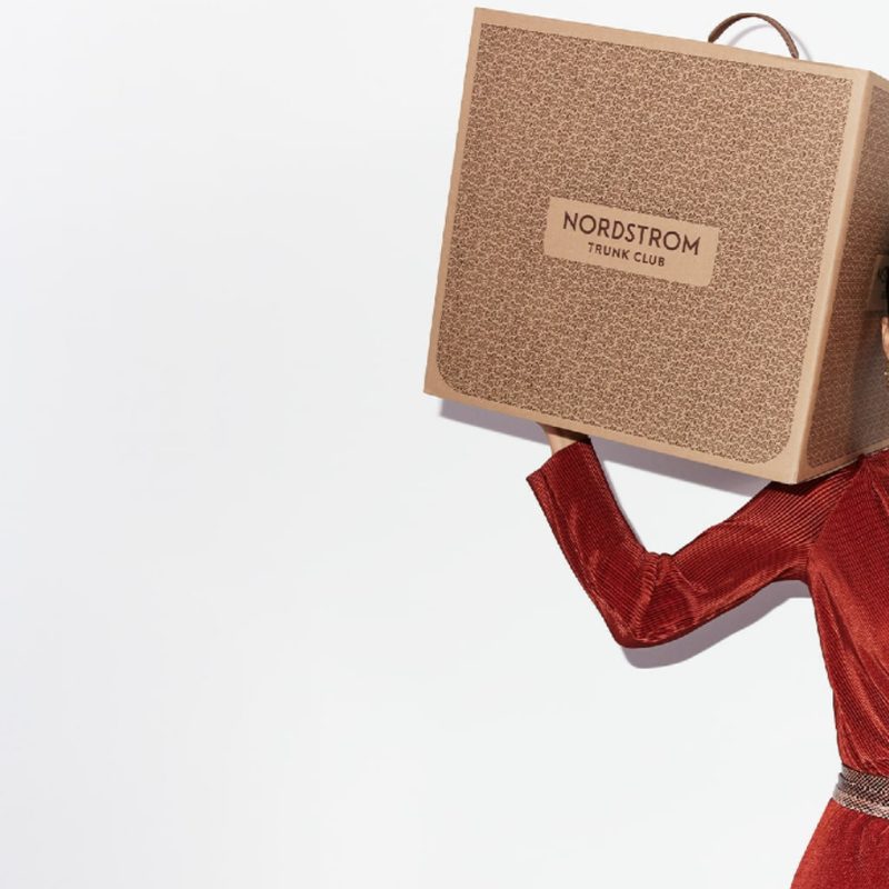 A woman laughing and holding a Nordstrom Trunk Club box.