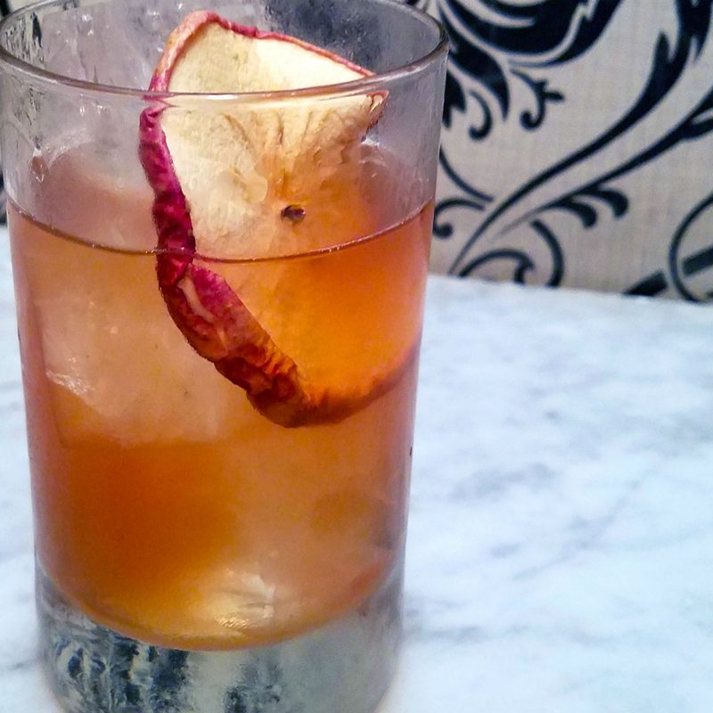 A glass of Almost Lost Lake with garnish on a table.