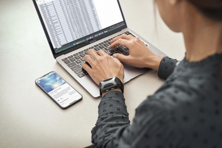 Man with Apollo Neuro device around his wrist while using a laptop.