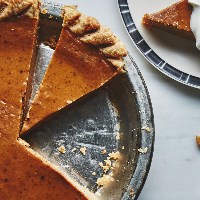 Pumpkin Pie on a table with one slice on the side.