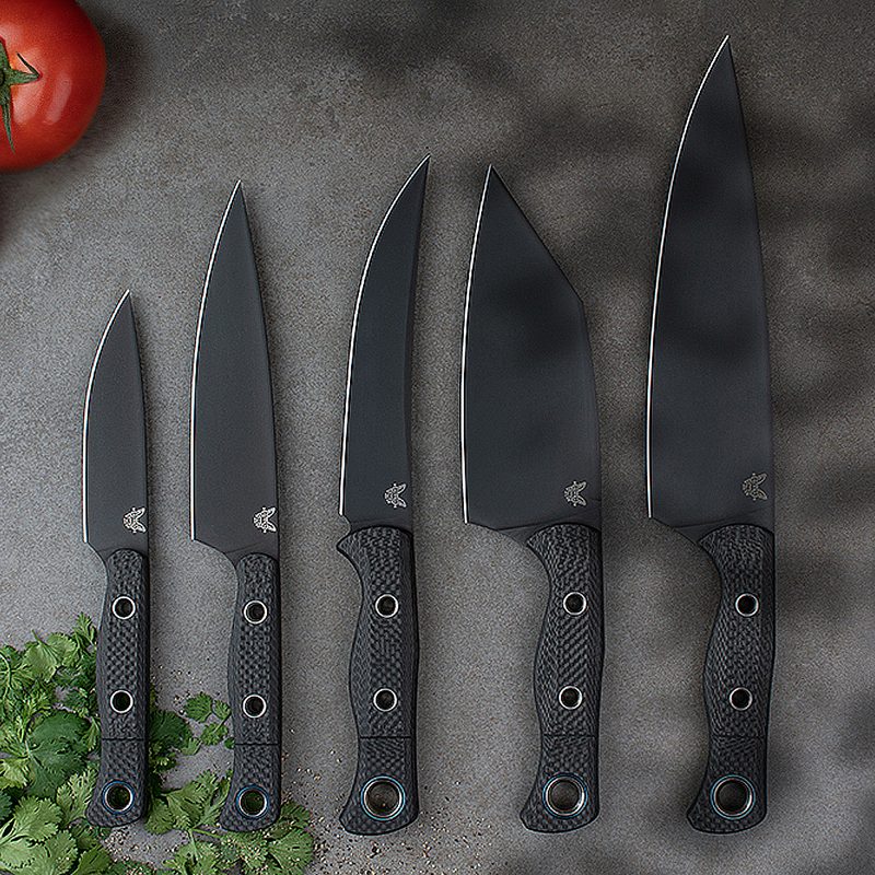 Five Benchmade knives on a table, with tomatoes and parsley leaves close to them.