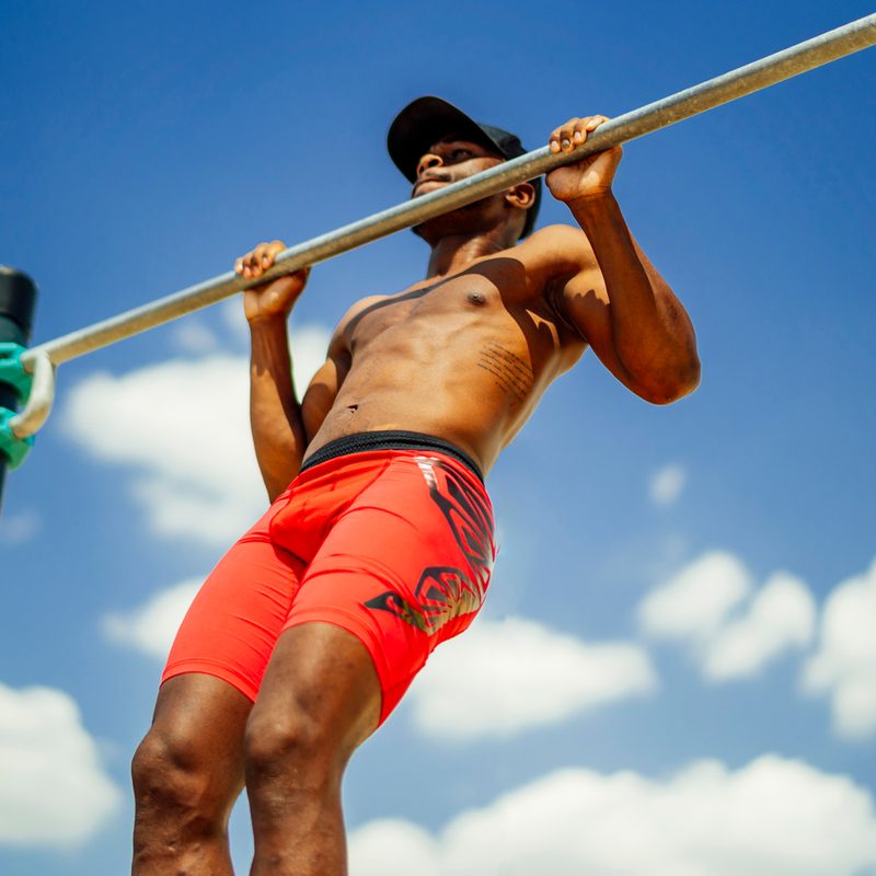 An athlete using a barbell outside on a sunny day.