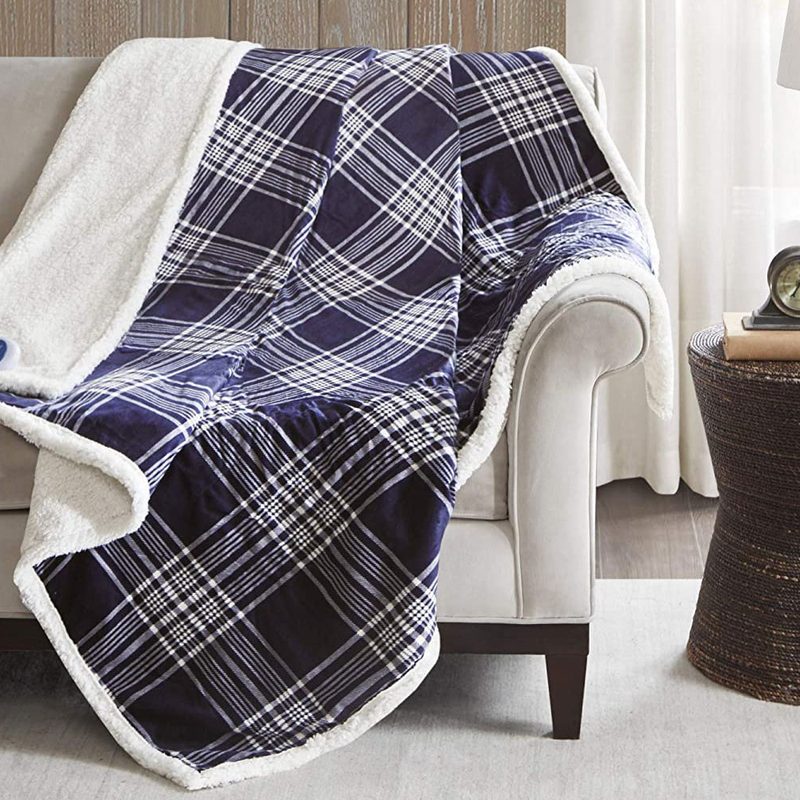 A heated blanked on a couch beside a side table with decor in a living room.