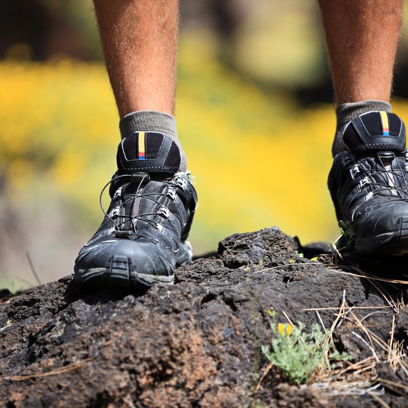 Close-up of a man wearing hiking shoes and standing atop a rock