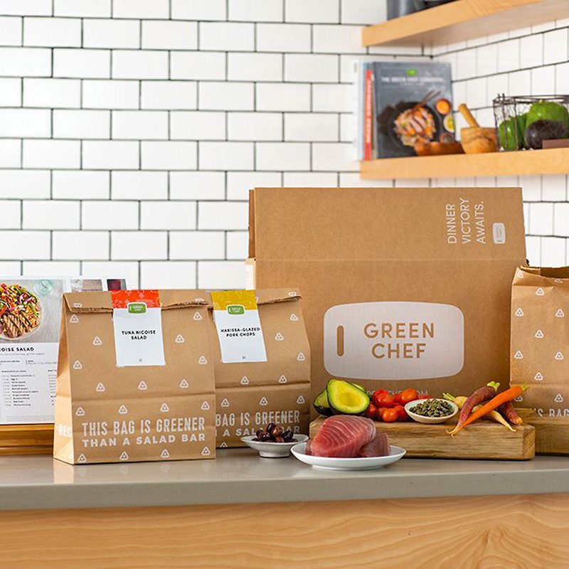 A box and three paper bags from Green Chef placed behind healthy foods.