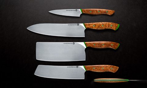 Set of kitchen knives sitting side by side on a black counter.