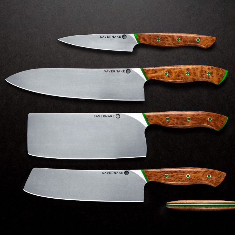 Set of kitchen knives sitting side by side on a black counter.