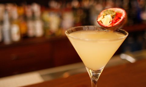A glass of passion fruit cocktail with garnish in a bar.