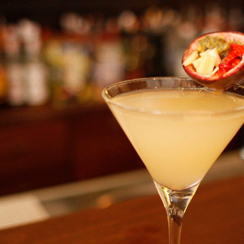 A glass of passion fruit cocktail with garnish in a bar.