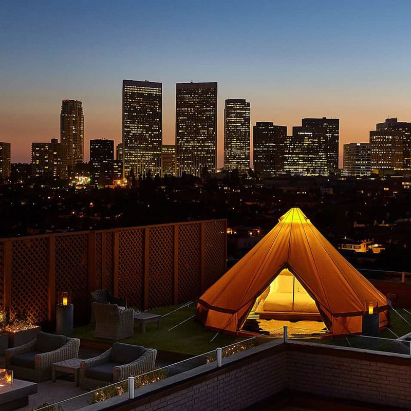 A bird's eve view of skyscrapers and a tent at the veranda in Beverly Wilshire at dusk.