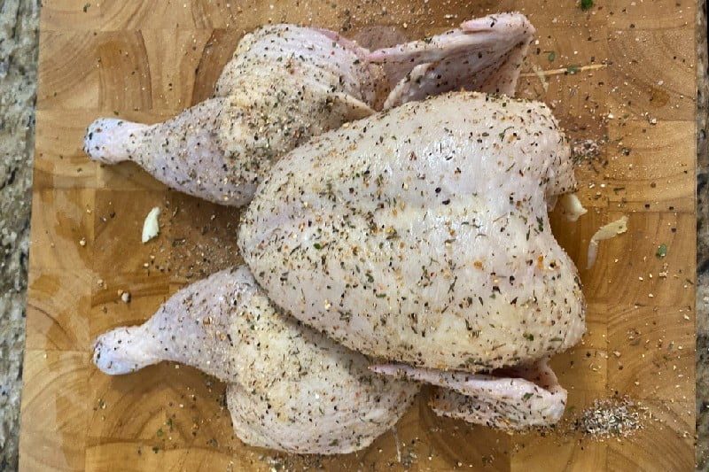 Seasoned chicken on cutting board.