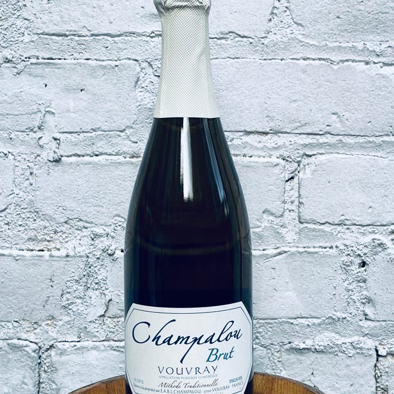 Bottle of Champalou | 'Vouvray Brut,' Vouvray, Loire Valley, France NV against a wall.