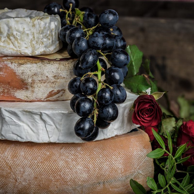 cheese wheels stacked on top of each other with a bunch of grapes hanging off them.