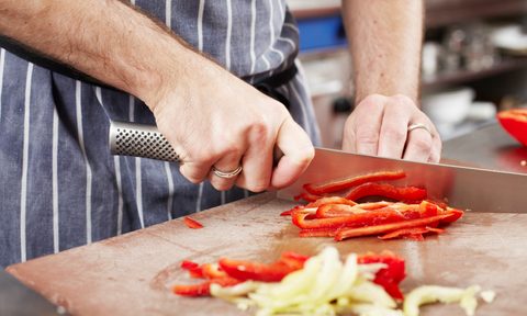 Chef chopping a vegetable with a knife.