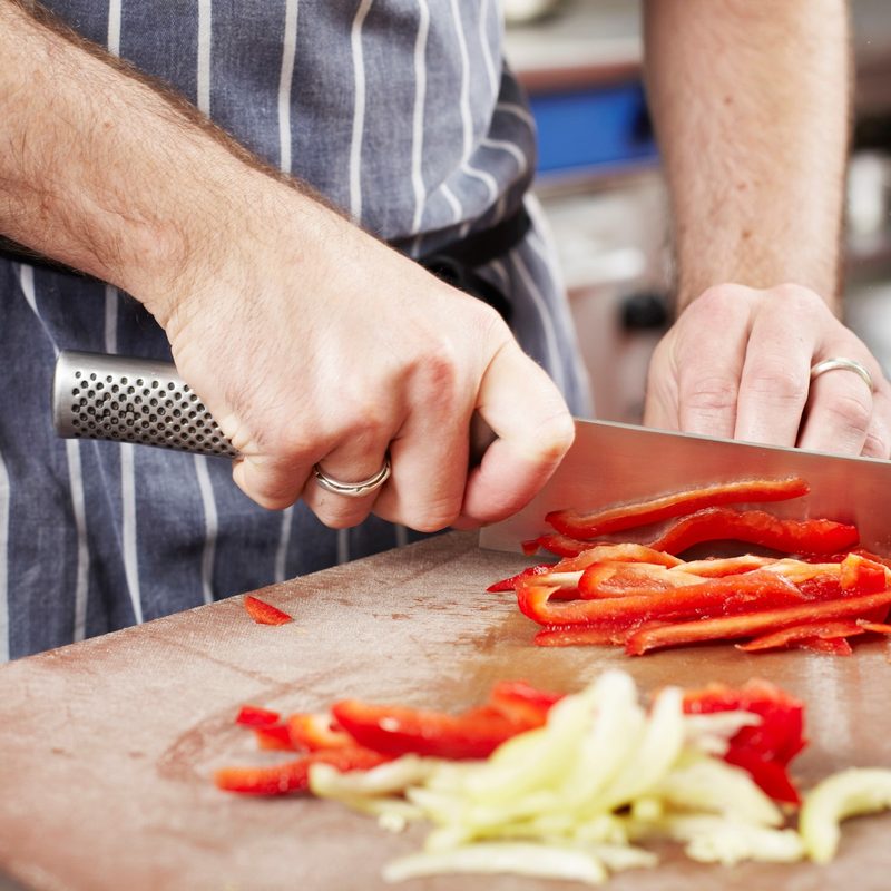 Chef chopping a vegetable with a knife.