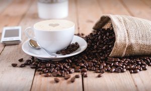 A cup of coffee beside spilled coffee beans