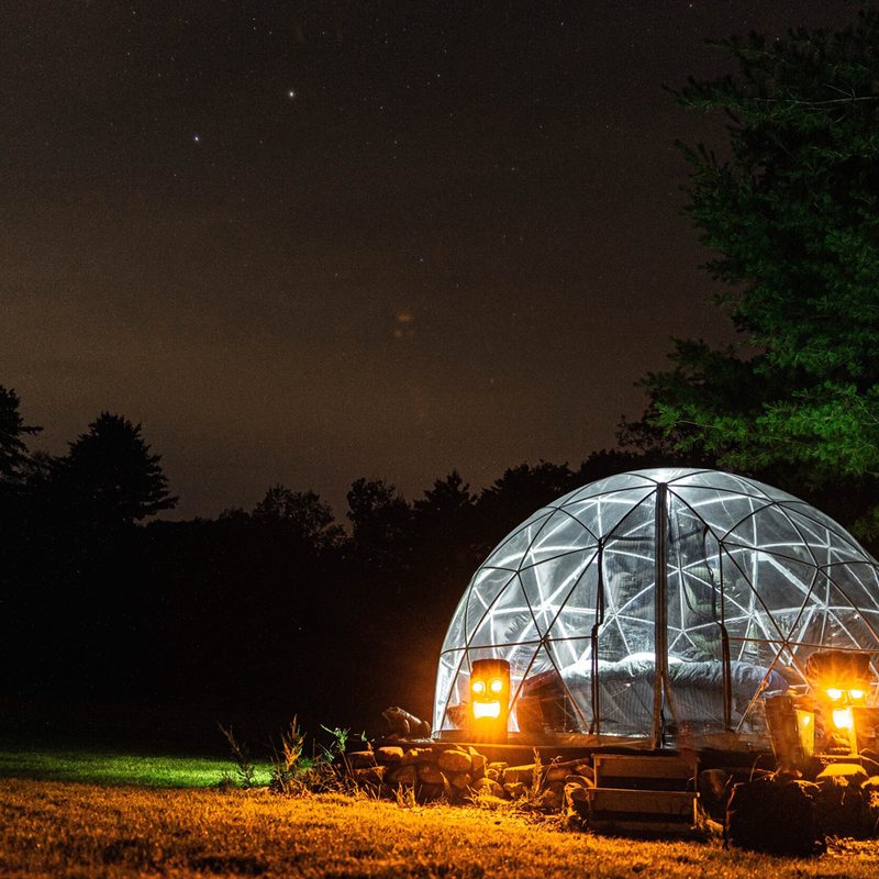 A lit up dome at the ComfyDome Glamping Hill-Side Site.
