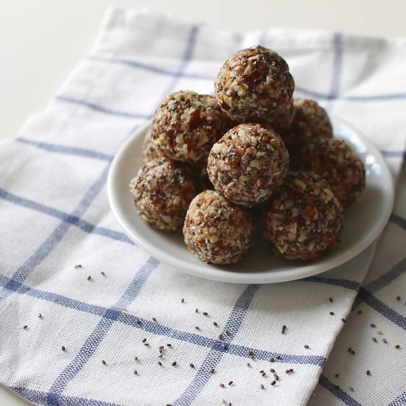 cranberry coconut protein balls sitting on a shallow plate on top of a checkered hand towel.