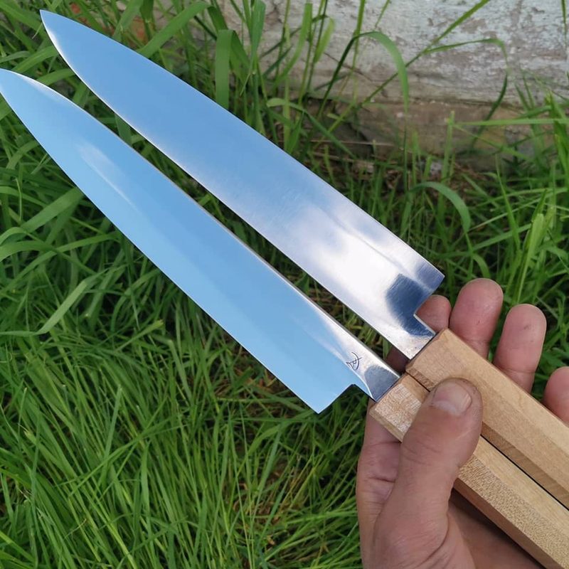 A hand holding two Dalman knives.