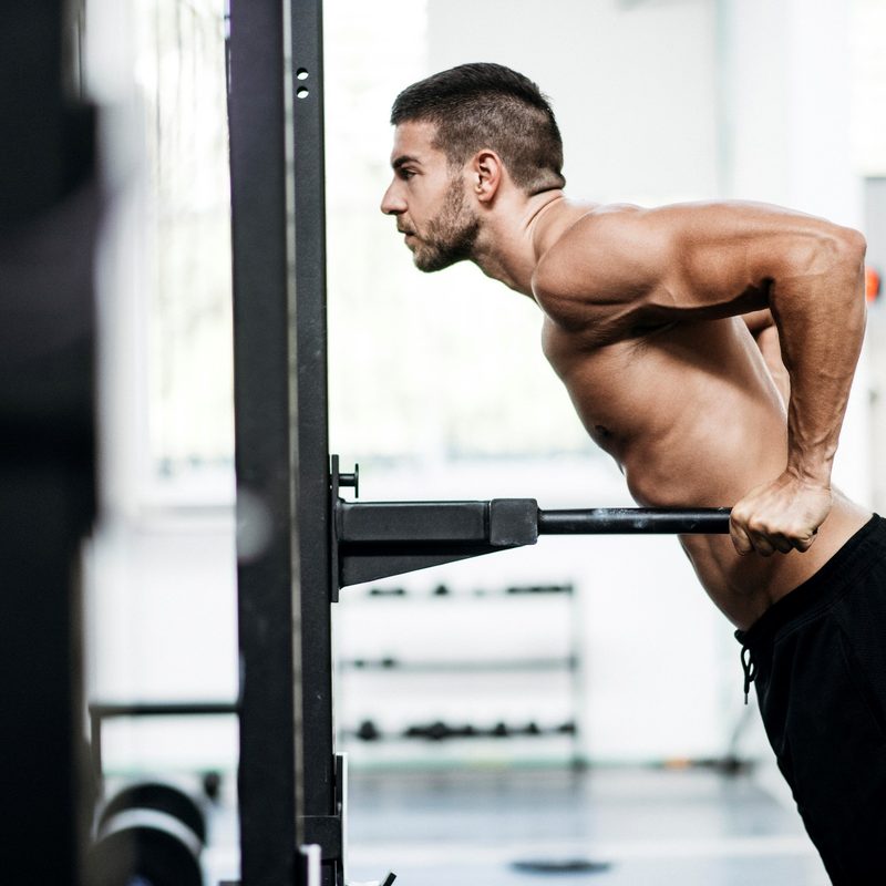 Man doing dips using gym equipment.