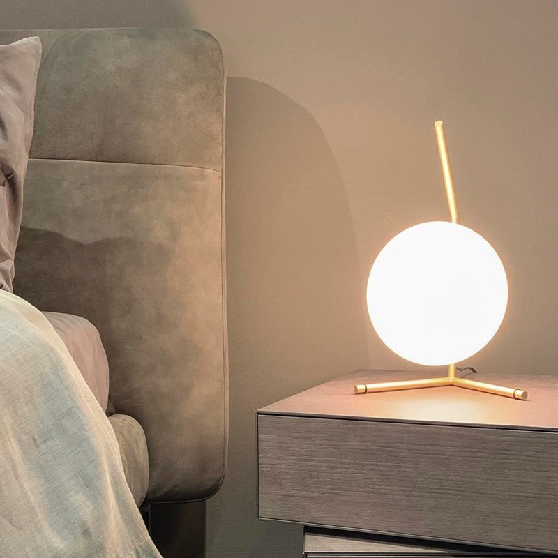 Light therapy lamp sitting on a nightstand next to a bed.