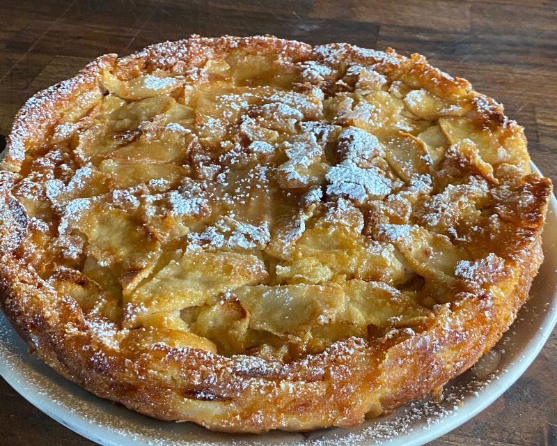 plated French Apple Cake dusted with powdered sugar on table.