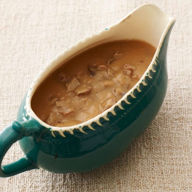 A giblet gravy in a gravy boat on a table cloth