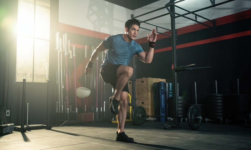 Athletic man doing high knees at a gym