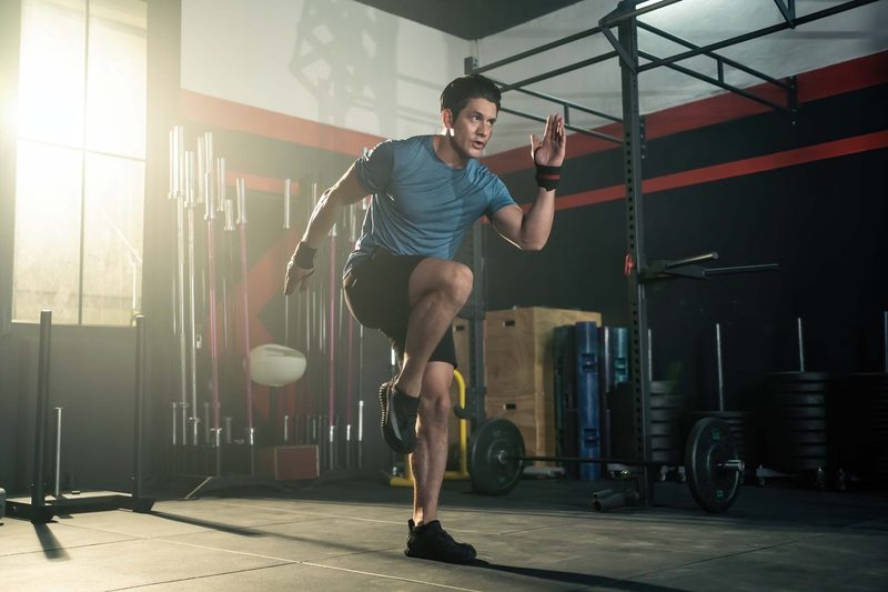 Athletic man doing high knees at a gym.