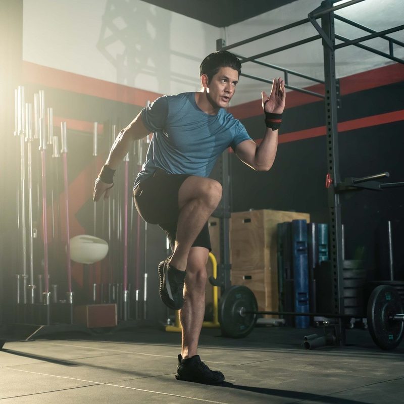 Athletic man doing high knees at a gym