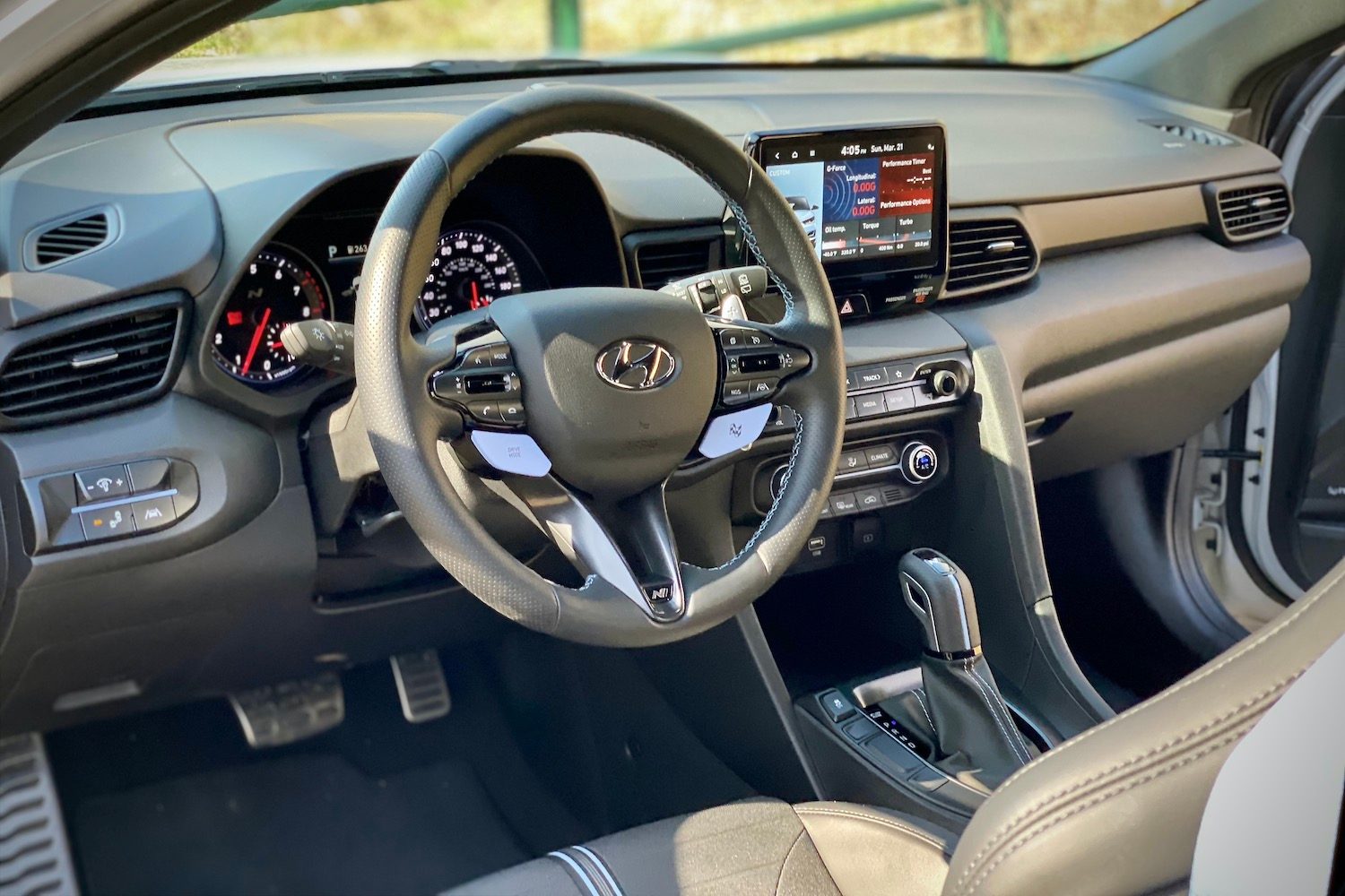 Hyundai Veloster N steering wheel close up with a fence in the background.